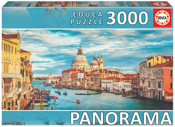 Grand Canal Venice 3000-piece jigsaw puzzle by Educa. The puzzle showcases a vibrant panorama of Venice, featuring colorful buildings lining the Grand Canal, gondolas, and the iconic domes of St. Mark's Basilica under a bright blue sky with scattered clouds. Ideal for puzzle enthusiasts and lovers of scenic landscapes.