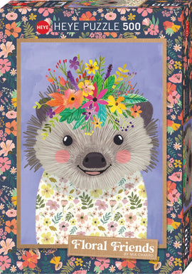 A colorful jigsaw puzzle box featuring a cute hedgehog with a floral crown. The hedgehog has a happy expression, with pink cheeks and is wearing a flower-patterned shirt. The background is a soft purple, adorned with vibrant floral motifs framing the hedgehog.