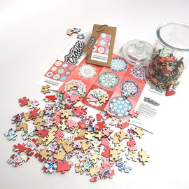 A colorful jigsaw puzzle titled '9 Mandalas' made by Trove, featuring an assortment of intricately designed wooden pieces in various shapes and colors. The scattered puzzle pieces are shown alongside a packaging card and a glass jar filled with additional pieces, all against a white background. The puzzle promises a creative and engaging activity for puzzle enthusiasts.