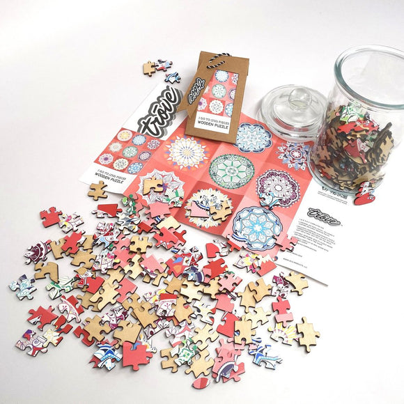 A colorful jigsaw puzzle titled '9 Mandalas' made by Trove, featuring an assortment of intricately designed wooden pieces in various shapes and colors. The scattered puzzle pieces are shown alongside a packaging card and a glass jar filled with additional pieces, all against a white background. The puzzle promises a creative and engaging activity for puzzle enthusiasts.