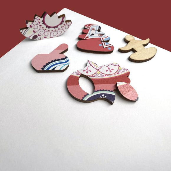 Various colorful jigsaw puzzle pieces featuring intricate mandala designs in pink, blue, and white. The pieces are made of sturdy material with rounded shapes that fit together to create a vibrant puzzle. The background is a neutral tone, allowing the vivid colors and patterns to stand out.