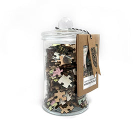A glass jar filled with intricately shaped wooden jigsaw puzzle pieces labeled '20th Century Transport' by Trove. The jar features a clear lid and a tag with the product's details, showcasing hints of vintage transport designs on the puzzle pieces inside.