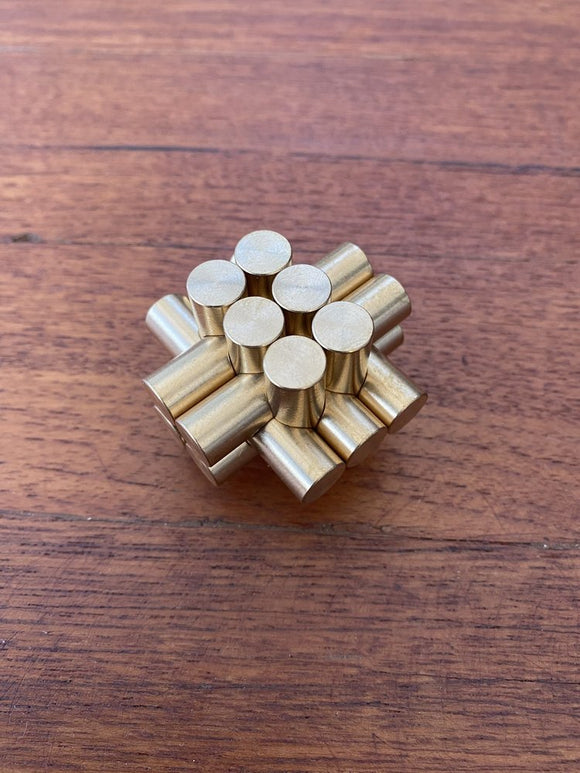 A mechanical puzzle made of brass, featuring an intricate design of cylindrical rods arranged in a cluster. The gold finish adds a touch of elegance, making it an attractive display piece as well as a challenging brain teaser.