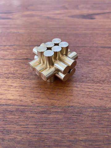 The Marmoset Burr Brass is a complex mechanical puzzle made of sleek brass pieces. It features a unique design with interlocking cylindrical sections that challenge users to find the solution through manipulation and spatial reasoning.