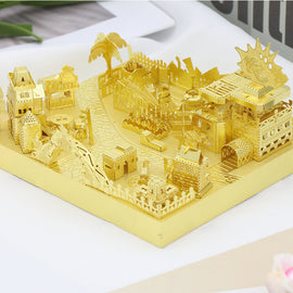 A detailed golden DIY kit featuring bumper cars, intricately designed with various miniatures of buildings, trees, and attractions arranged in a playful landscape. The kit showcases a fairground scene, perfect for creative assembly and decoration.