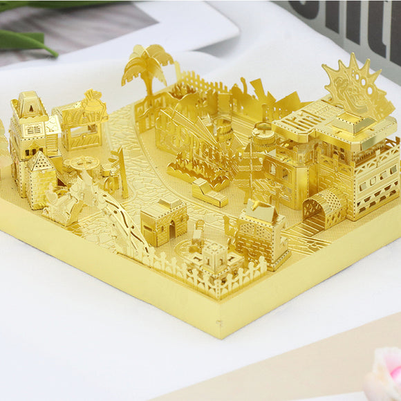 A detailed golden DIY kit featuring bumper cars, intricately designed with various miniatures of buildings, trees, and attractions arranged in a playful landscape. The kit showcases a fairground scene, perfect for creative assembly and decoration.