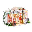 A detailed Honey Ice Cream Shop model kit from Robotime, featuring a charming storefront with pink windows, a sign, and decorative plants. It includes an interior scene with a counter, ice cream decorations, and a small bear statue, showcasing an inviting and whimsical atmosphere for creative DIY enthusiasts.