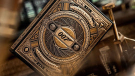 James Bond 007 playing card deck by Theory 11, featuring intricate gold and black designs. The card box displays the iconic 007 logo and decorative elements, emphasizing a high-quality collectible for card game enthusiasts.