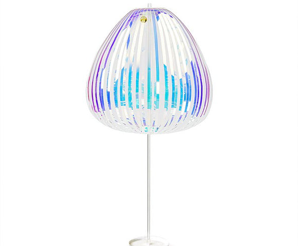The Rainbow Stick Deluxe by Prodia is a vibrant, translucent lamp featuring a unique design with colorful vertical strips of varying widths. Its modern shape resembles a jellyfish or a blooming flower, casting a playful glow in any environment, making it a perfect decorative and ambient lighting piece.