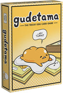 The Gudetama Tricky Egg Card Game box features playful illustrations of Gudetama, a lazy egg character, lounging on a white blanket with cards peeking out underneath. The bright yellow background and whimsical design highlight the fun nature of the game, inviting players to enjoy a cheerful experience together.