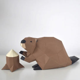 A low poly craft DIY kit featuring a cute beaver figure, animated and playful, sitting beside a stylized log. The beaver, made of geometric shapes, showcases a brown color with black accents and a light-colored log. Ideal for creative crafting enthusiasts.