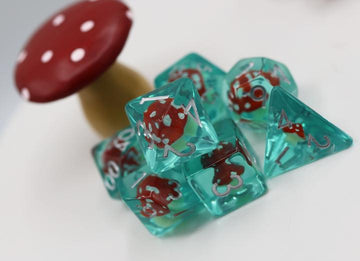 The Power Up Mushroom RPG Dice Set by Foam Brain features a collection of colorful polyhedral dice in teal with red mushroom designs and white numbers, accompanied by a decorative red and white mushroom piece.