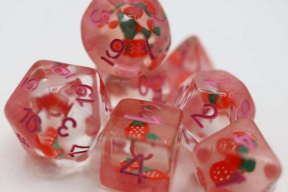A colorful Strawberry Shortcake RPG Dice Set featuring translucent pink dice adorned with strawberry and green leaves designs. The dice display numbers in vibrant purple. Ideal for tabletop RPG enthusiasts looking to add a whimsical touch to their game.