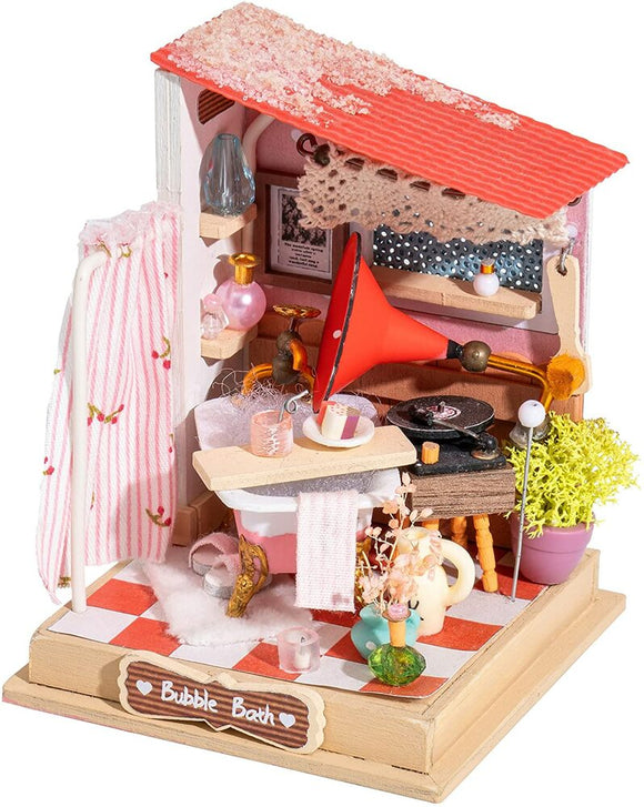 A beautifully crafted miniature Bubble Bath model kit by Robotime, showcasing a cozy bathroom scene. It features a white bathtub with a pink base, pink floral decorations on the wall, a red vinyl horn speaker, delicate flowers, and assorted beauty products on shelves. The cozy design includes a checkered floor and various charming details that create a whimsical atmosphere for DIY enthusiasts.