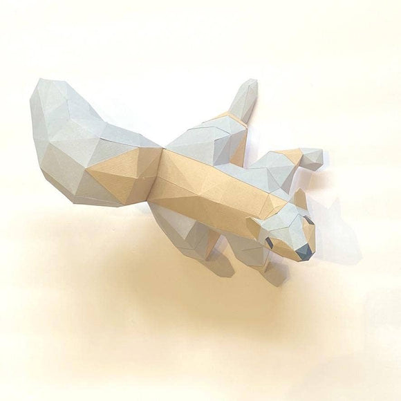 A low poly craft model of a squirrel on a light background. The squirrel features geometric shapes in grey and tan colors, capturing a playful, artistic design. Ideal for DIY enthusiasts or as a unique decor piece.