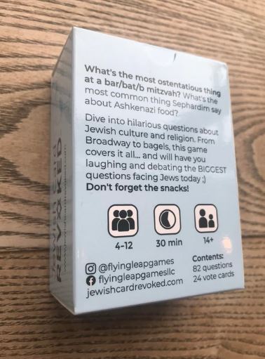 A game box for 'Jewish Card Revoked' by Flying Leap Games, featuring a humorous design. The back of the box includes questions related to Jewish culture, religion, and traditions, encouraging players to laugh and debate about common Jewish experiences. It highlights gameplay details like player count (4-12), game duration (30 minutes), and age recommendation (14+).