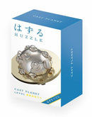 The Cast Planet mechanical puzzle by Hanayama is shown in its packaging. The box features a blue and white design with 'CAST PLANET' boldly displayed on the front. The puzzle itself, a metallic orb with intricate interlocking pieces, sits prominently on a golden base, highlighting its complexity and challenge. The packaging includes a star rating, indicating difficulty level, and 'Huzzle' branding, appealing to puzzle enthusiasts.
