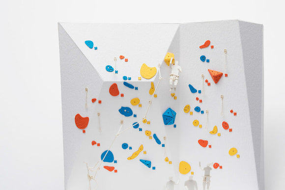 The Sport Climbing Model by TERADA MOKEI is a detailed DIY kit featuring a climbing wall with colorful holds in red, blue, and yellow. Small figurines are positioned on the wall, simulating a climbing scene. The model showcases intricate designs and adds a playful aspect to home decor, perfect for indoor enthusiasts.