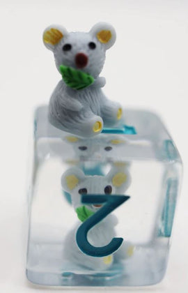 Close-up of the Koala RPG Dice Set by Foam Brain, featuring a cute koala figurine atop a clear die. The die shows a blue number '2' with a sitting koala underneath, highlighting the playful design perfect for tabletop role-playing games.