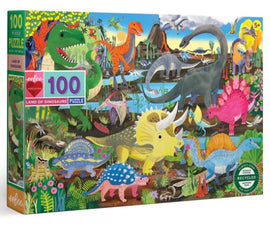 Colorful jigsaw puzzle titled 'Land of the Dinosaurs' by Eeboo, featuring numerous dinosaurs in a vibrant prehistoric landscape, designed for ages 5 and up. The box shows a variety of species including Triceratops, T-Rex, and Stegosaurus, with rich foliage and mountains in the background.