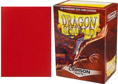 A box of Dragon Shield card sleeves in Matte Crimson, displaying 100 standard size sleeves. The box features a vibrant design with a dragon and the logo prominently displayed.