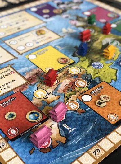 A colorful board game set on a detailed map featuring different regions with player pieces in various colors. Cards and tokens are visible, showcasing gameplay elements. The board includes areas for scoring and actions, enhancing the visual appeal of strategic play.