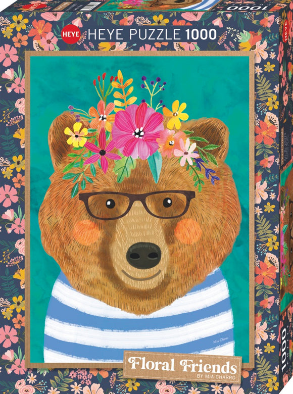 Heye Floral Friends Gentle Bruin jigsaw puzzle box featuring a whimsical bear wearing glasses and a striped shirt, surrounded by vibrant flowers. The artwork is colorful and inviting, designed by Mia Charro. The puzzle contains 1000 pieces and showcases a beautiful floral theme.