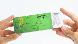 A person holding a FlipBoku: Winsor McCay flipbook, showcasing a vibrant green cover featuring animated sketches and the name Winsor McCay prominently displayed. The design highlights early animation art, hinting at the creative storytelling within.