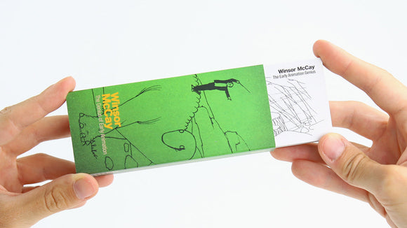 A person holding a FlipBoku: Winsor McCay flipbook, showcasing a vibrant green cover featuring animated sketches and the name Winsor McCay prominently displayed. The design highlights early animation art, hinting at the creative storytelling within.