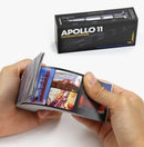 A person holds a FlipBoku: Apollo 11 50th Anniversary Edition flipbook, showcasing various iconic images from the Apollo 11 mission. The box is visible in the background with its vibrant design featuring the Apollo rocket and the title 'Apollo 11 - The Iconic Footage'. Perfect for space enthusiasts and collectors.