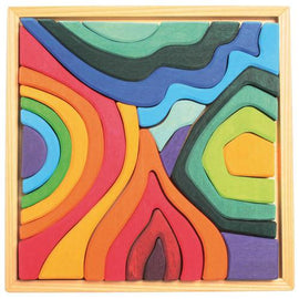 A vibrant and colorful Small Four Elements Building Set by Grimm's, featuring pieces in the shapes of natural elements like waves and mountains. The set is composed of various colors including green, blue, red, yellow, and orange, designed to engage children in creative play and enhance their fine motor skills. The pieces fit together into a wooden frame, promoting imaginative storytelling and exploration of elements like earth, air, fire, and water.