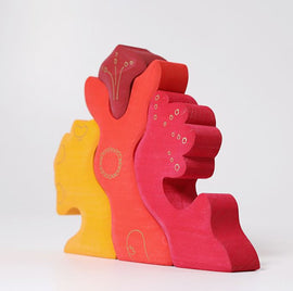 A colorful wooden puzzle by Grimm's called Casa Glora. The design features vibrant hues of yellow, red, and orange, with playful shapes resembling abstract hands or figures, ideal for imaginative play and developing fine motor skills in children.