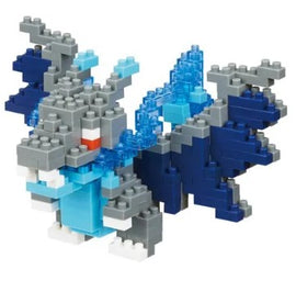 A detailed view of the Nanoblock Mega Charizard X DIY kit, showcasing the intricate assembly of colorful blocks in shades of grey, blue, and white, depicting a stylized dragon-like creature with large wings and tail.