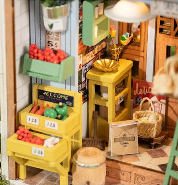 A detailed model kit of a morning fruit store, featuring vibrant miniatures of fruits and vegetables arranged in wooden crates. The store has a colorful sign that reads 'WELCOME' and shelves adorned with various decorations. A charming atmosphere is created by the arrangement of baskets and accessories, highlighting the intricate craftsmanship of the Robotime DIY kit.