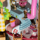 An intricate DIY model kit representing a sweet jam shop. Features a charming little machine with pink accents, jars labeled with jam, and a decorative setup with vibrant colors, perfect for crafting enthusiasts.