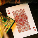 A vibrant High Victorian playing card featuring the Ace of Hearts, designed by Theory 11. The card showcases intricate detailing with rich red and gold elements, set against a textured background, surrounded by additional decorative cards and books.