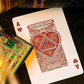 A vibrant High Victorian playing card featuring the Ace of Hearts, designed by Theory 11. The card showcases intricate detailing with rich red and gold elements, set against a textured background, surrounded by additional decorative cards and books.