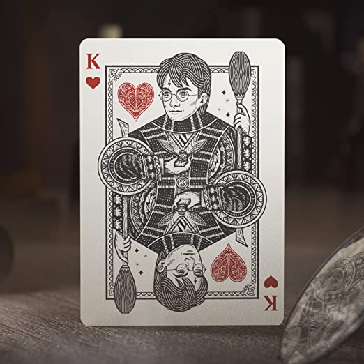 A detailed playing card featuring Harry Potter as the King of Hearts. The design showcases Harry with round glasses and a broomstick, highlighting intricate patterns and vibrant colors.