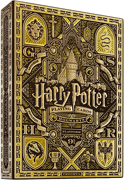 Harry Potter-themed playing cards packaging showcasing intricate designs featuring Hogwarts castle, house crests, and themed illustrations, primarily in yellow and gold colors. Crafted by Theory 11, this collectible deck is perfect for fans of the wizarding world.