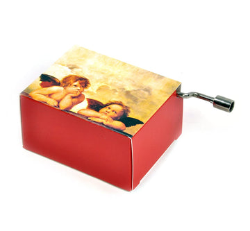 A red music box featuring a design of two cherubic angels from Raphael's artwork. The music box has a winding key on the side, inviting nostalgic melodies.