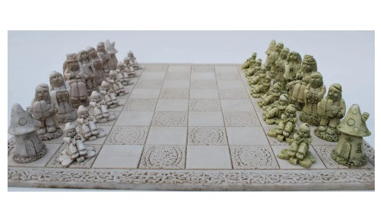 A beautifully crafted Leprechaun Chess set from O'Gowna Studios featuring intricately designed pieces resembling leprechauns and mushrooms. The chessboard has an ornate border and a classic checkered pattern, showcasing a thematic Irish folklore style. The pieces are displayed in two colors, creating a visually striking game scene.