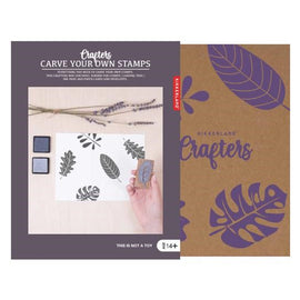 Carve Your Own Stamps kit by Kikkerland Design Inc. featuring tools for stamp carving, a block of rubber for stamping, and ink pads. Package shows an example of stamped leaf designs.