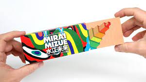 A colorful Mirai Mizue Flipbook box being held by two hands. The box features vibrant artwork with abstract designs in various colors, highlighting the playful nature of the flipbook experience. The package emphasizes creativity and entertainment.