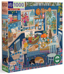 Eeboo's Blue Kitchen jigsaw puzzle featuring a vibrant kitchen scene filled with colorful dishes, fruits, vegetables, and adorable cats lounging on the floor. The artwork showcases intricate details of a cozy kitchen, with blue tones and cheerful decor, ideal for puzzle enthusiasts and art lovers alike.
