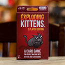 Exploding Kittens 2 Player Edition game box featuring a cartoon cat holding a grenade. The packaging indicates it is a family-friendly card game designed for 2 players ages 7 and up, emphasizing fun and humor around kittens and explosions.