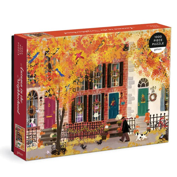 The 'Autumn in the Neighborhood' jigsaw puzzle by Galison features a vibrant autumn scene with colorful leaves, houses adorned with fall decorations, and people walking their dogs. This 1000-piece puzzle captures the cozy essence of fall in a charming neighborhood setting.