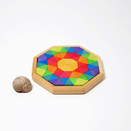 Colorful Small Octagon puzzle by Grimm's featuring a vibrant arrangement of triangular wooden pieces in shades of green, blue, yellow, orange, and red. The octagonal base is made of light wood and is accompanied by a small seashell, highlighting the playful design.