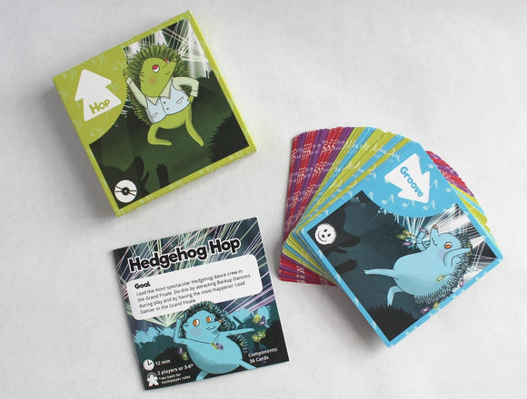 Hedgehog Hop game by Fight in a Box featuring colorful cards and a goal card. The box showcases a hedgehog dressed in a vest, dancing among vibrant lights, appealing to 2-6 players with quick gameplay and fun graphics.