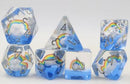 A Beautiful Day RPG Dice Set by Foam Brain displayed on a white background. The set includes various polyhedral dice featuring a design with clouds and vibrant rainbow colors. Each die showcases clear resin with colorful rainbow and silver numbering, making them visually appealing for tabletop gaming.