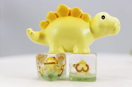 A vibrant Stegosaurus RPG dice set featuring a cheerful yellow dinosaur figurine resting on two transparent dice with golden numbers. The playful design adds a fun element to tabletop gaming, perfect for friends and family game nights.